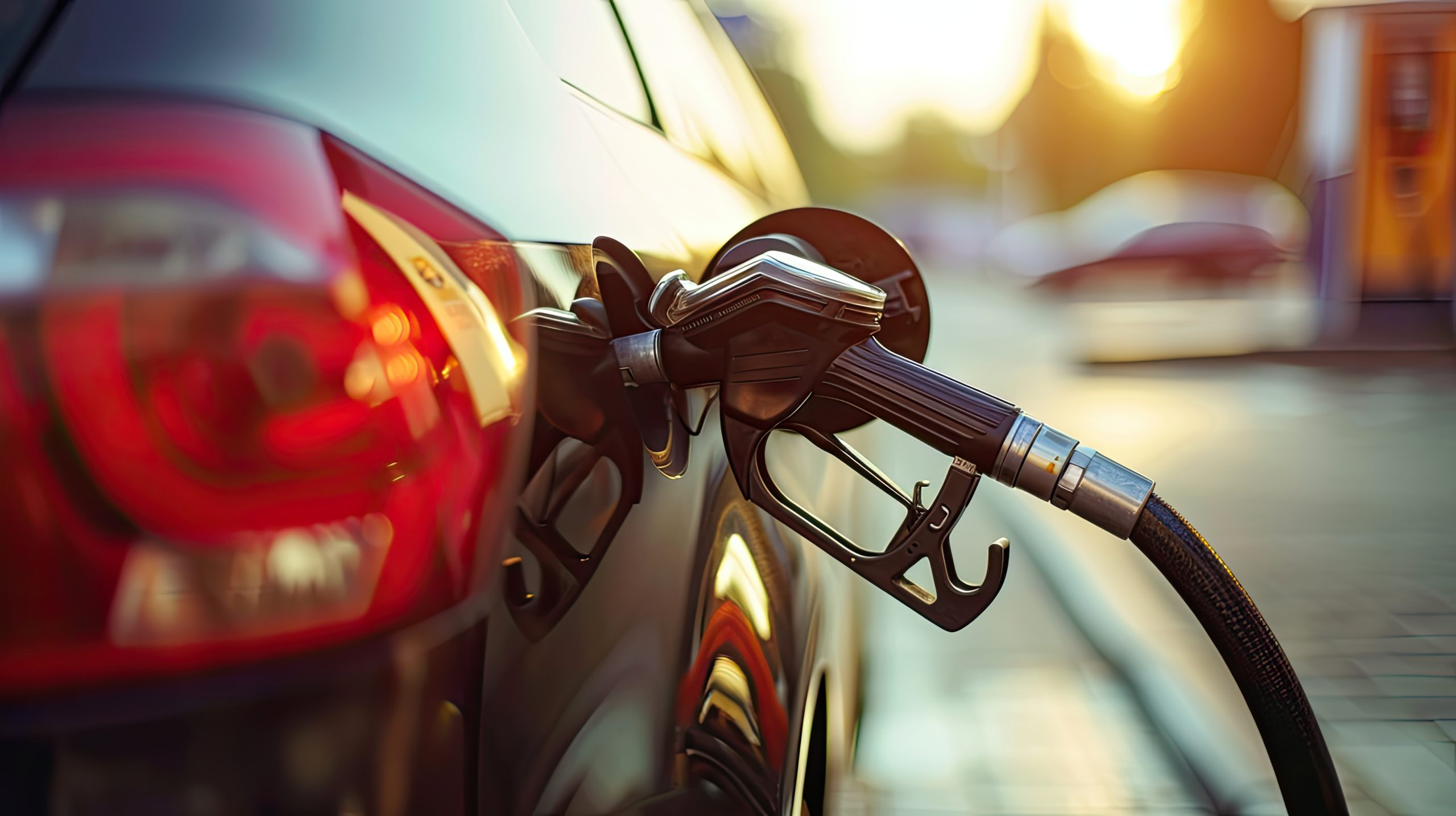 Gun petrol in the tank to fill. Car refueling concept Close-up of a fuel pump nozzle inserted into a car's gas tank at a gas station, with warm sunlight reflecting off the vehicle's surface.